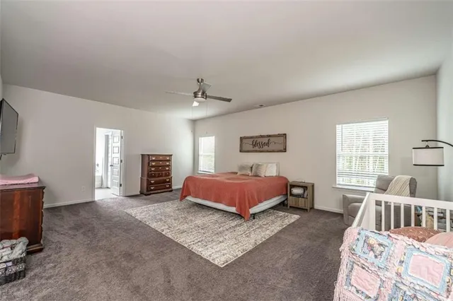 a spacious bedroom with a bed a window and dresser