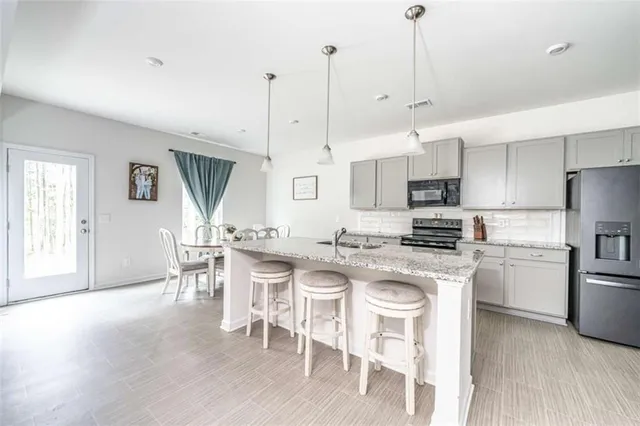 a kitchen with stainless steel appliances granite countertop a stove a refrigerator a kitchen island a sink and a refrigerator