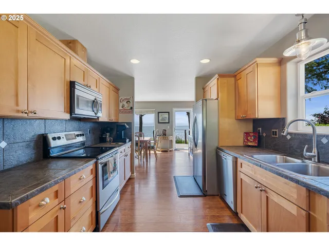 a kitchen with stainless steel appliances granite countertop a refrigerator a sink dishwasher a oven with white cabinets and wooden floor