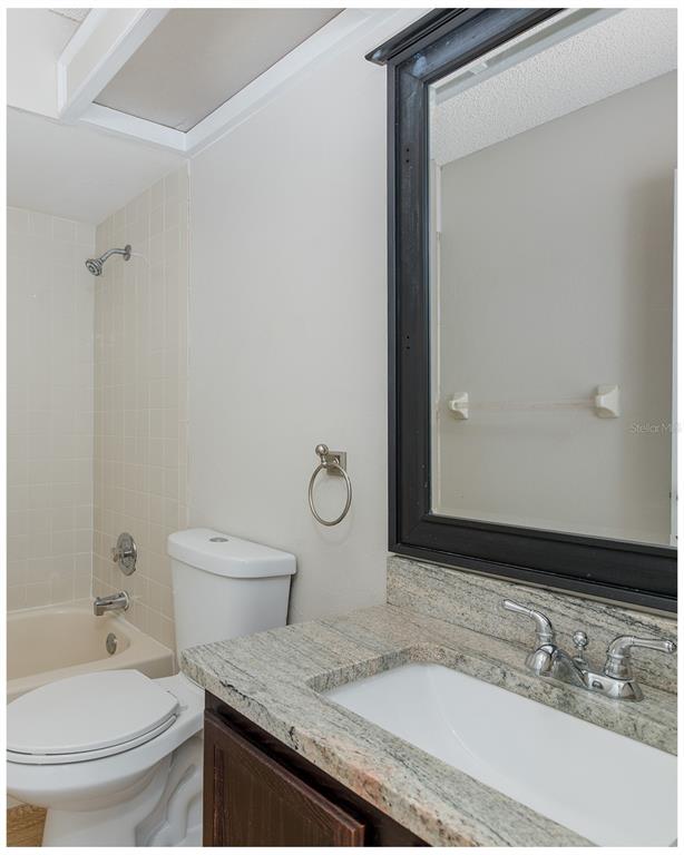 7900 Hardwick Drive, Unit 827 New Port Richey, FL 34653 - Photo 23 of 27 a bathroom with a granite countertop sink toilet and shower