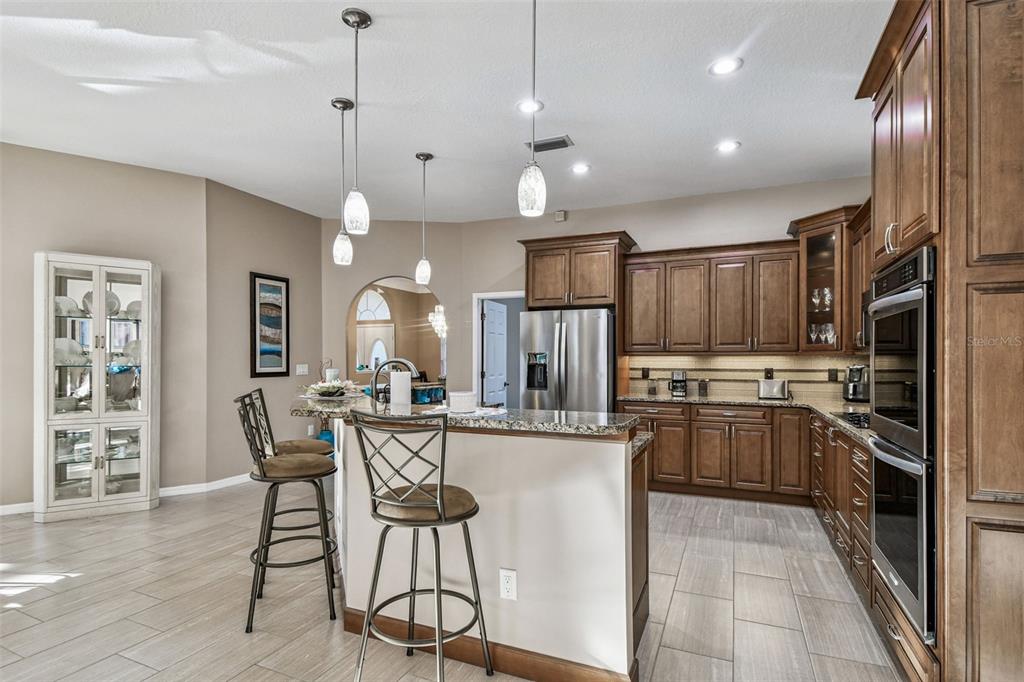 1955 Dunloe Circle Dunedin, FL 34698 - Photo 23 of 94 a kitchen with stainless steel appliances a stove center island a refrigerator and wooden cabinets