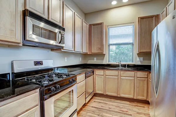 a kitchen with stainless steel appliances granite countertop a stove a microwave and a refrigerator