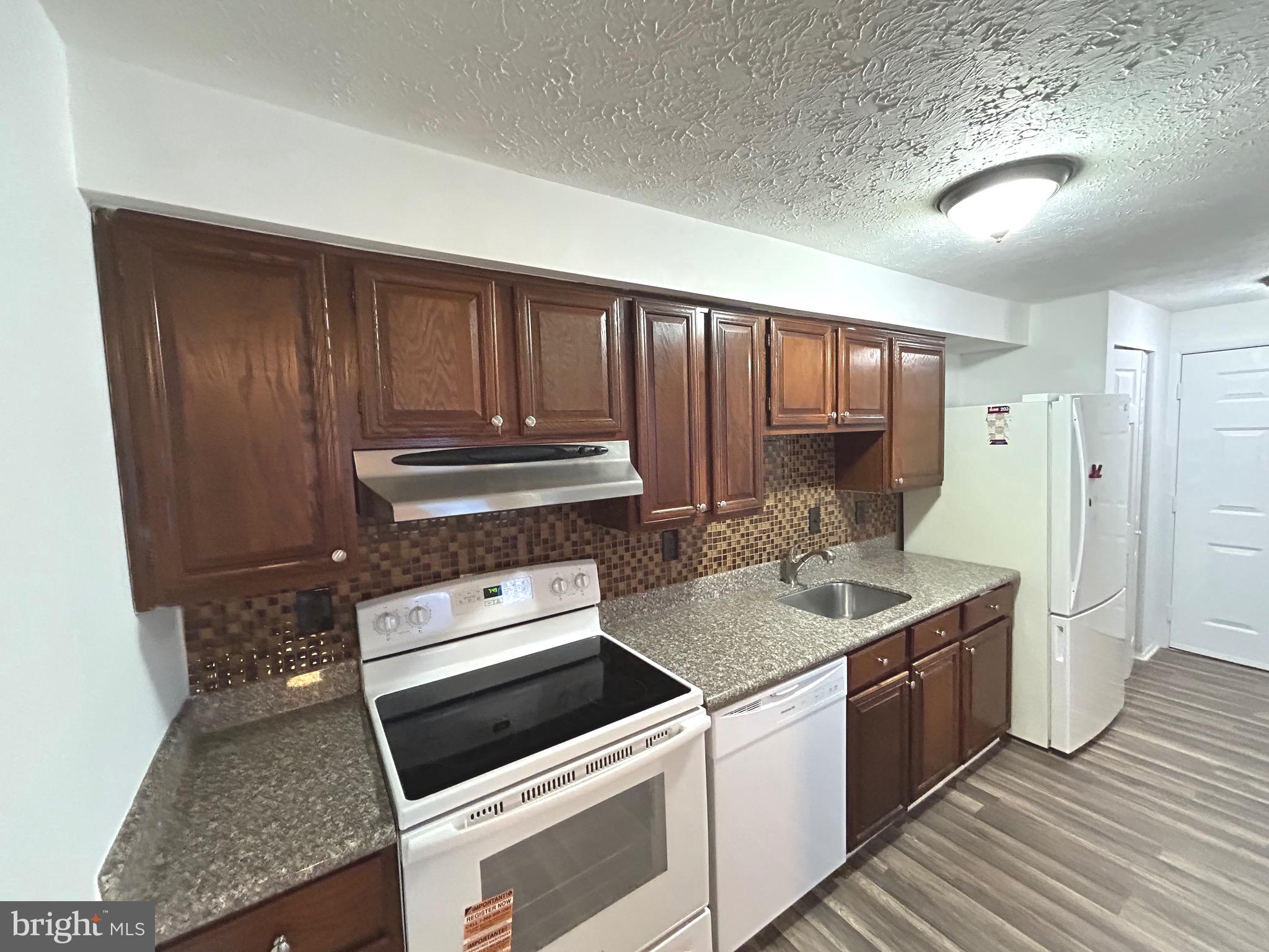 12405 Hickory Tree Way, Unit 613 Germantown, MD 20874 - Photo 20 of 39 a kitchen with wooden cabinets and a stove top oven