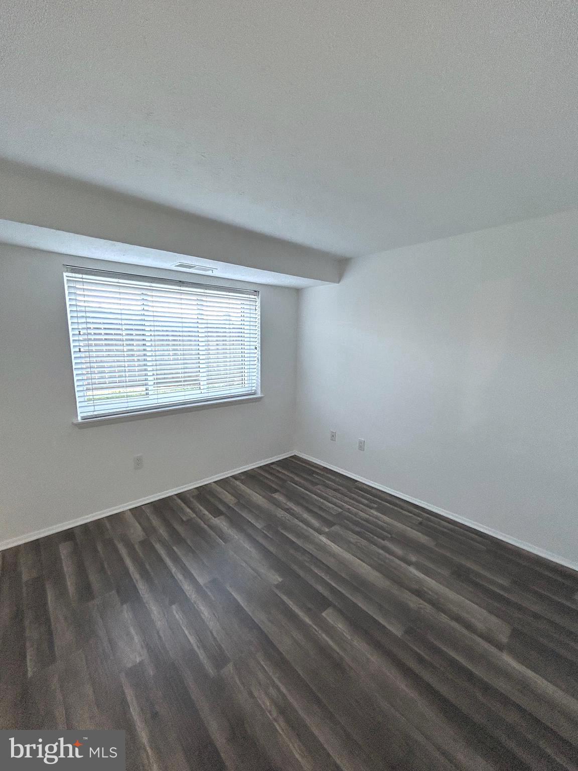 12405 Hickory Tree Way, Unit 613 Germantown, MD 20874 - Photo 22 of 39 a view of an empty room with wooden floor and a window
