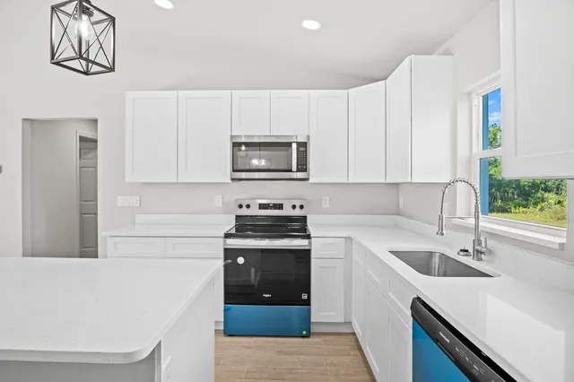 a kitchen with a sink dishwasher a stove top oven a refrigerator and cabinets with wooden floor