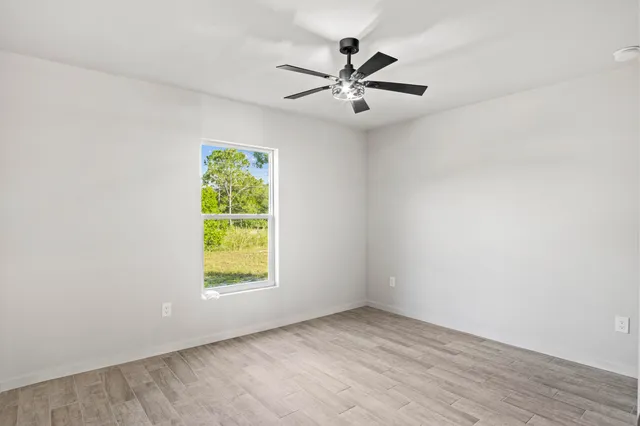 an empty room with window and ceiling fan