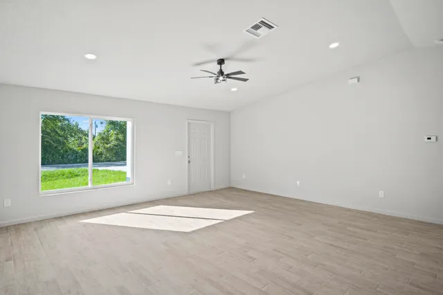 an empty room with a window and a ceiling fan