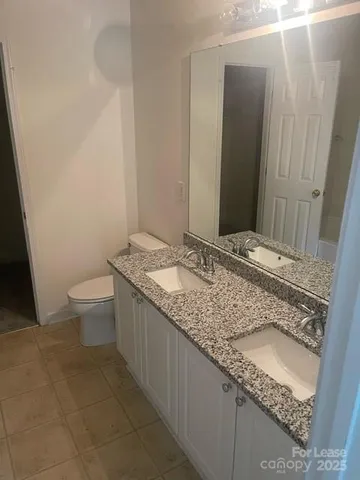 a bathroom with a granite countertop sink a toilet and a mirror