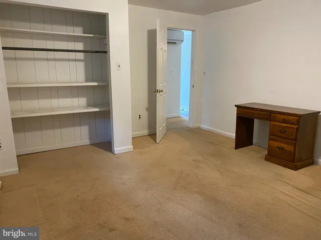 a view of an empty room with closet and a window