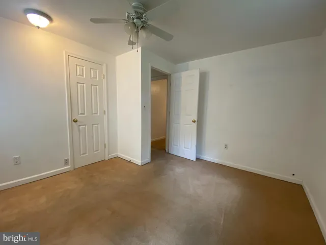an empty room with closet and a chandelier fan