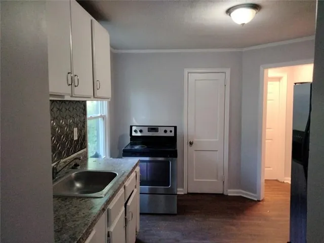 a view of a refrigerator in kitchen and an empty room