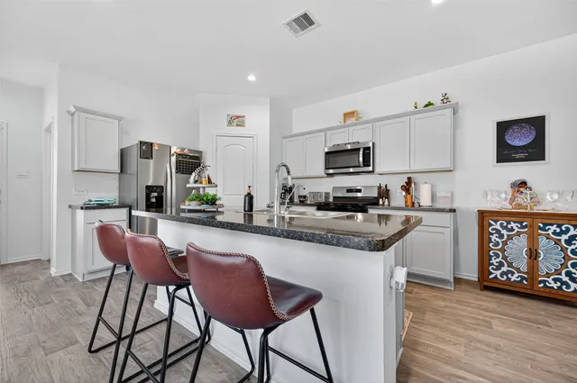 a kitchen with stainless steel appliances granite countertop a table and chairs in it