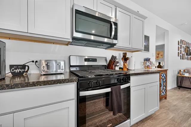 a kitchen with stainless steel appliances granite countertop white cabinets and a stove top oven