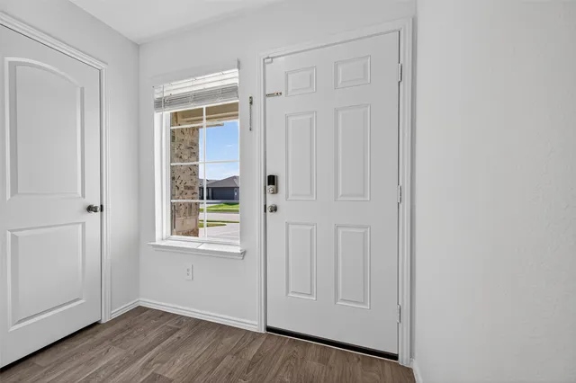 an empty room with wooden floor closet and windows