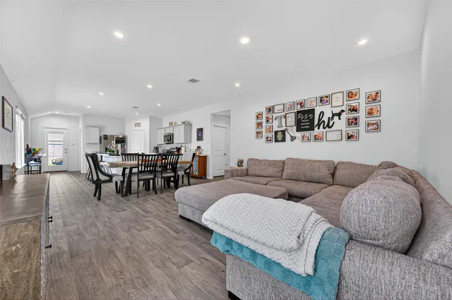 a living room with furniture and kitchen view with wooden floor