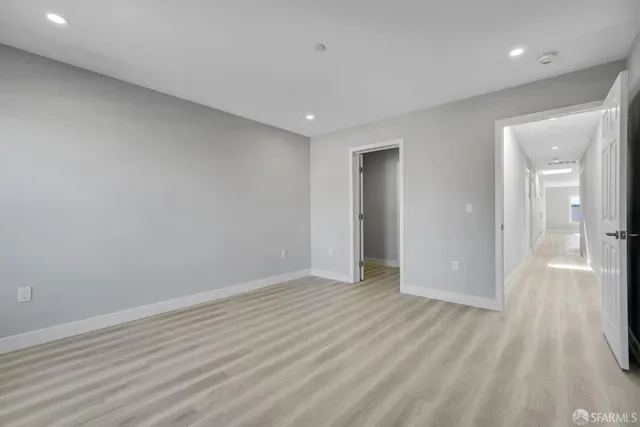 a large white kitchen with a stove a sink dishwasher and a refrigerator with wooden floor