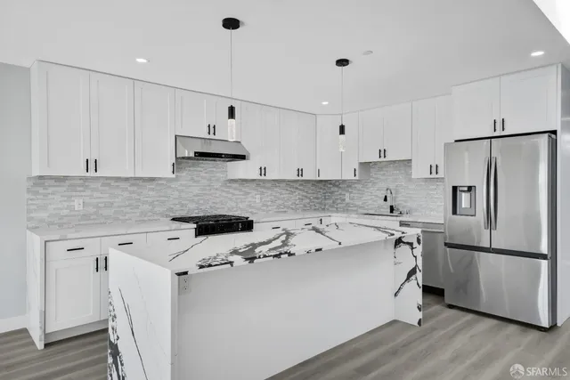 a large white kitchen with a white wooden cabinets and stainless steel appliances