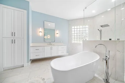 a bathroom with a granite countertop double vanity sink a mirror and a bathtub