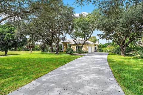 a view of a house with a big yard and large trees