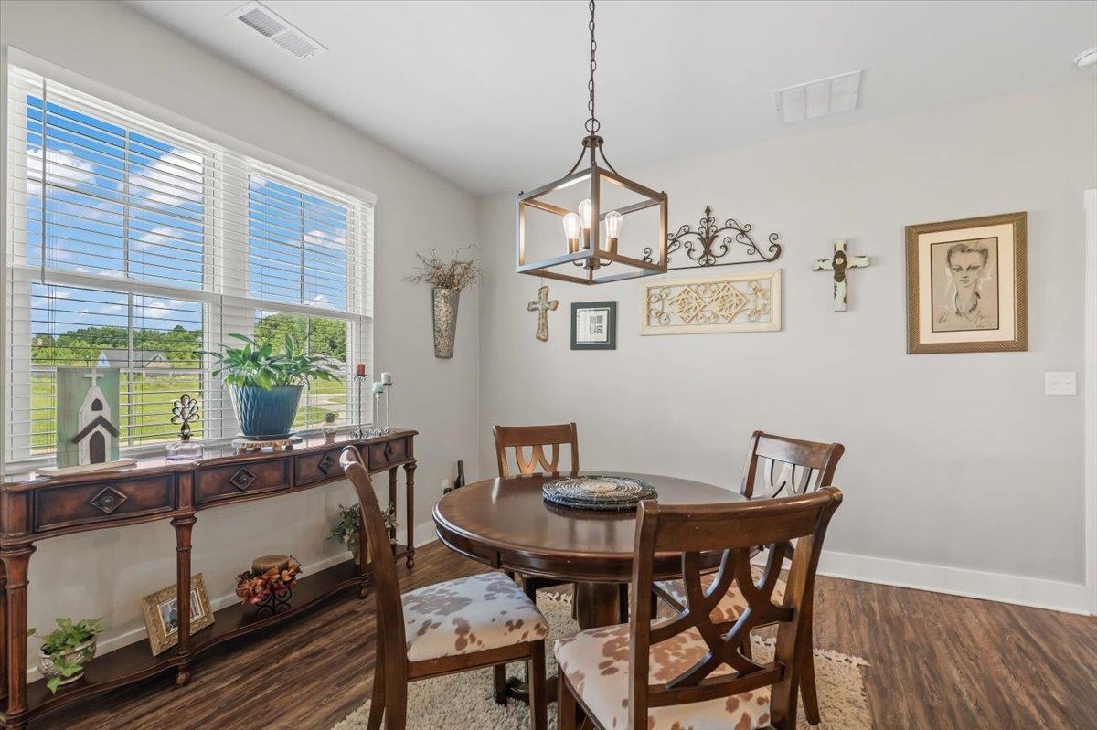 415 Abbey Road, Unit D Munford, TN 38058 - Photo 12 of 35 Dining area featuring wood-finish flooring, a contemporary chandelier, light gray wall paint, white baseboards, and a large window with blinds