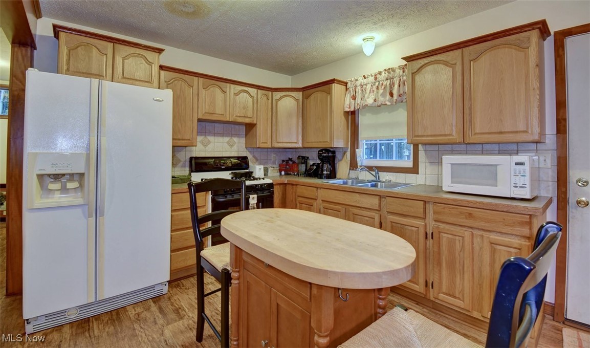 Green Road Tippecanoe, OH 44699 - Photo 33 of 50 Kitchen with white appliances, light wood-style floors, backsplash, light countertops, and a textured ceiling