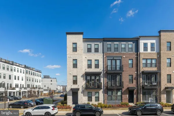 a front view of a building with lot of cars and trees