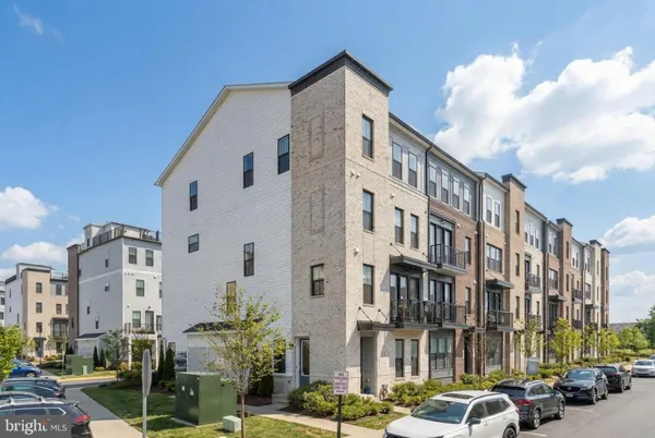 a front view of a building with lot of cars and trees
