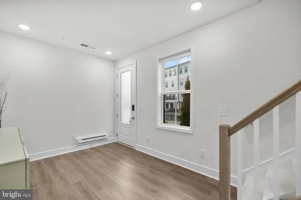 a view of an empty room with wooden floor and stairs