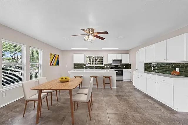 a kitchen with stainless steel appliances granite countertop a stove a sink a dining table and chairs