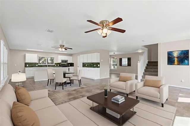 a living room with furniture a rug kitchen view and a chandelier