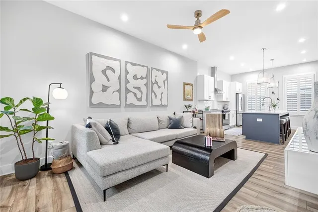 a living room with furniture potted plant and kitchen view