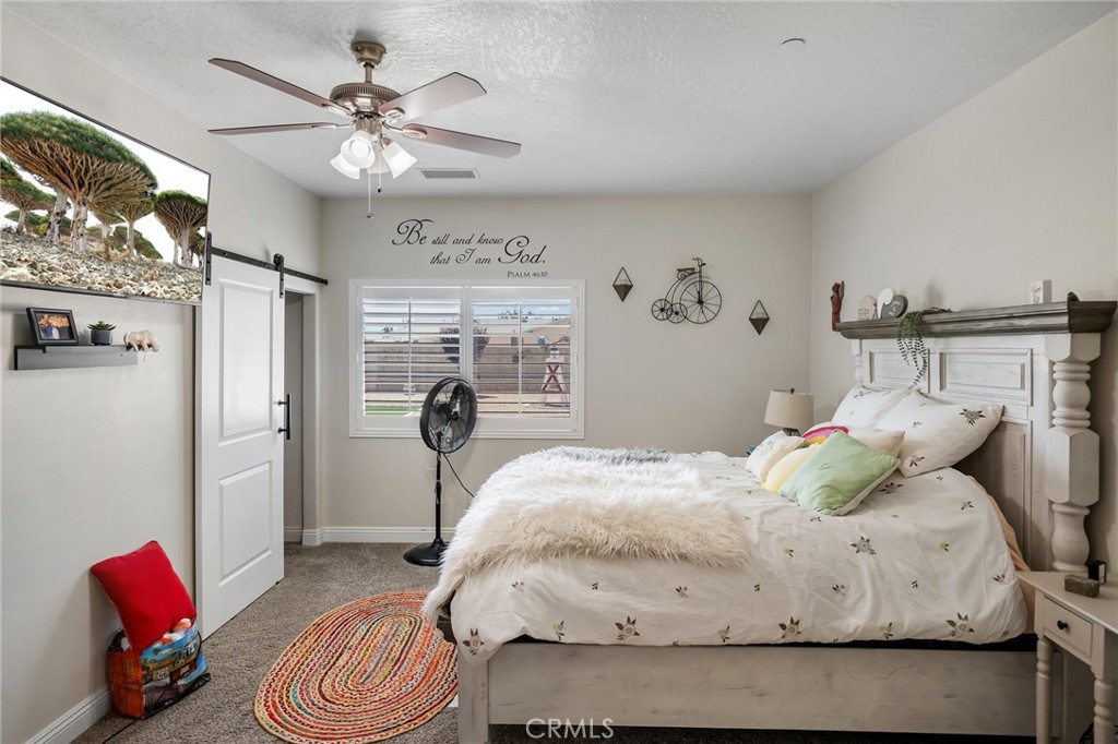 13178 Setancket Road Apple Valley, CA 92308 - Photo 16 of 24 a bedroom with a bed and a chandelier