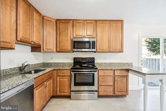 a kitchen with granite countertop a stove top oven a sink dishwasher and cabinets with wooden floor
