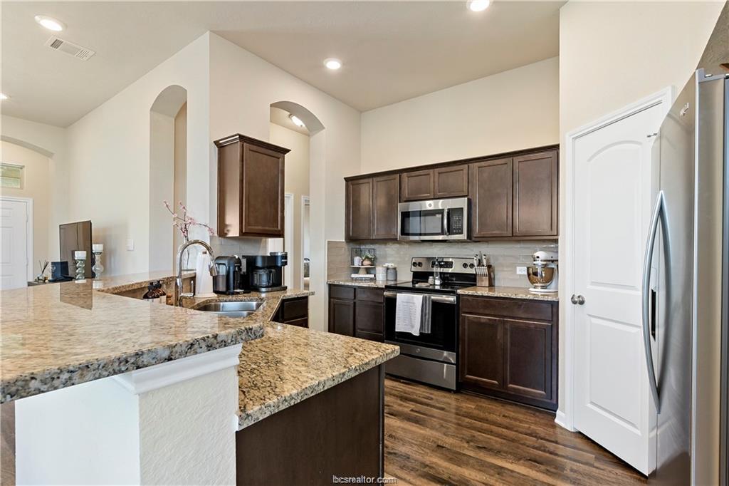 2000 Bleeker Cove Bryan, TX 77807 - Photo 11 of 24 a kitchen with stainless steel appliances granite countertop a sink stove microwave and refrigerator