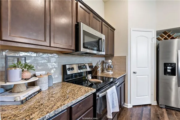 a kitchen with stainless steel appliances granite countertop a stove a refrigerator and a wooden cabinets