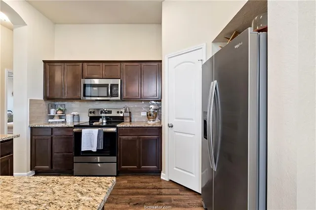 a kitchen with stainless steel appliances granite countertop a refrigerator and a stove top oven