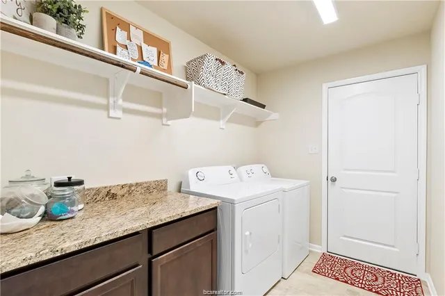 a utility room with granite countertop cabinets washer and dryer