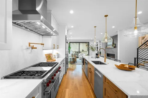 a kitchen with stainless steel appliances a stove a sink a refrigerator and chairs