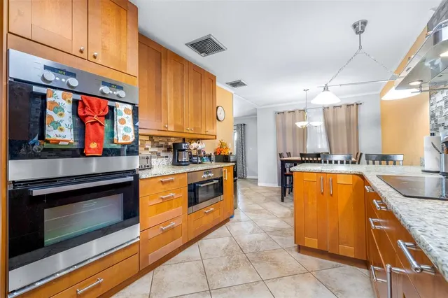 a large kitchen with granite countertop a stove a sink and a microwave