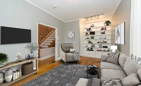 a living room with furniture a flat screen tv and a floor to ceiling window