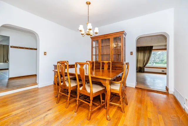 a dining room with furniture a chandelier and wooden floor