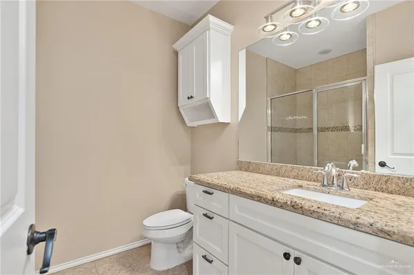 a bathroom with a granite countertop sink mirror vanity and toilet