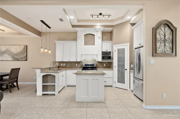 a large white kitchen with a stove a refrigerator and a fireplace