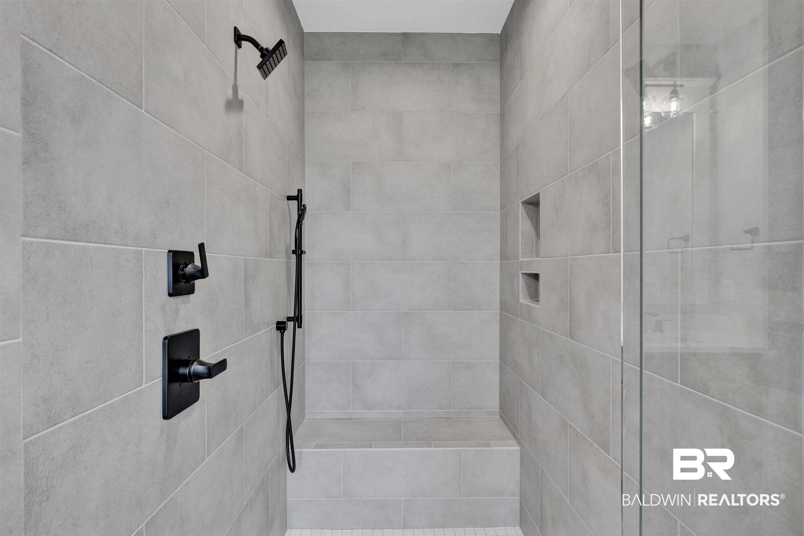 27371 Patch Pl Loop Daphne, AL 36526 - Photo 55 of 63 Tiled shower with a built-in bench, matte black fixtures, recessed shelving, and a frameless glass enclosure