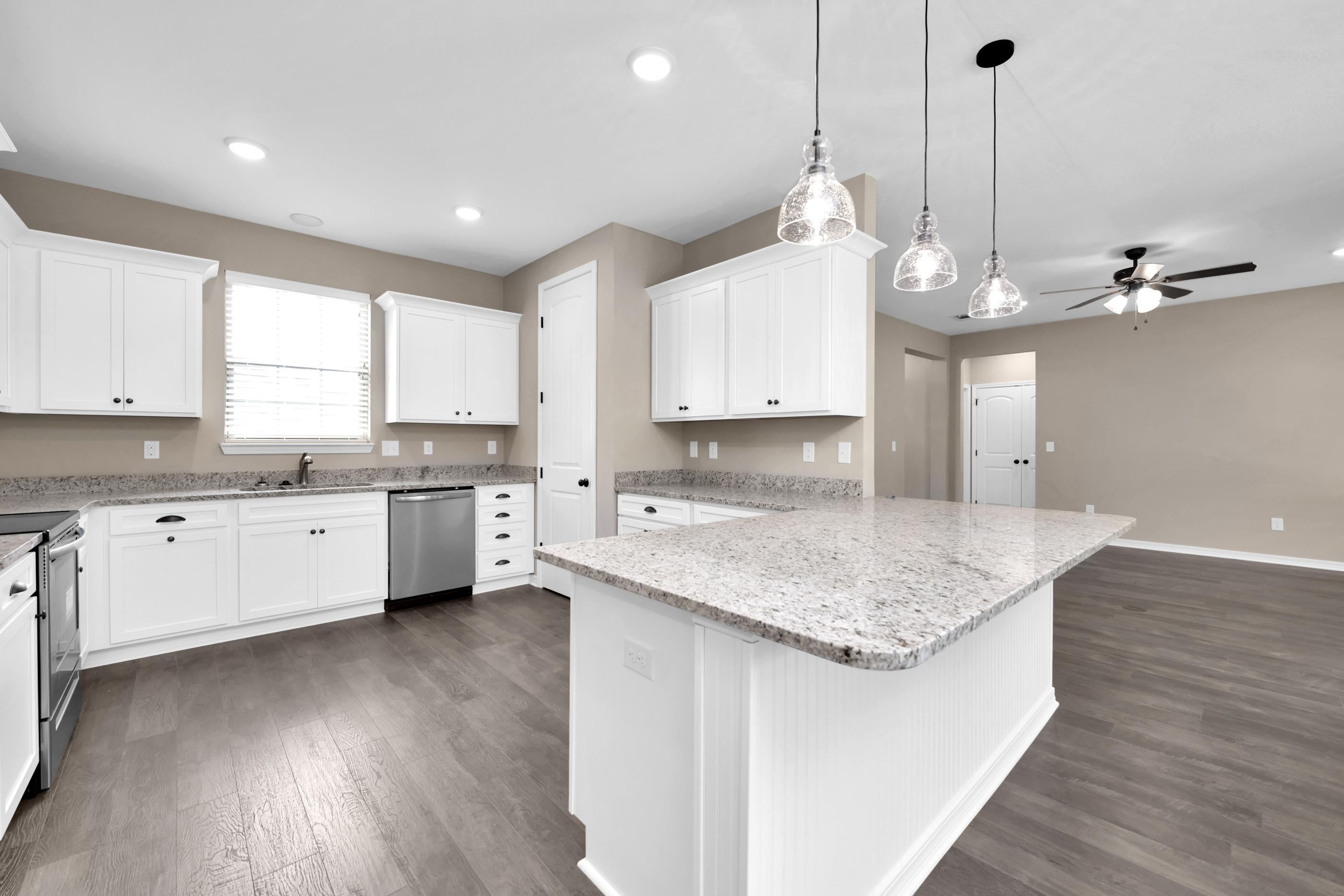 6195 Timberland Ridge Drive Crestview, FL 32539 - Photo 14 of 39 a kitchen with a white center island a sink dishwasher and a stove with wooden floor