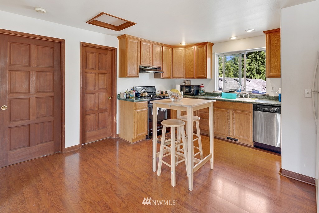 12008 Gibson Road Everett, WA 98204 - Photo 20 of 32 a kitchen with stainless steel appliances granite countertop a stove top oven a sink dishwasher and a refrigerator with wooden floor