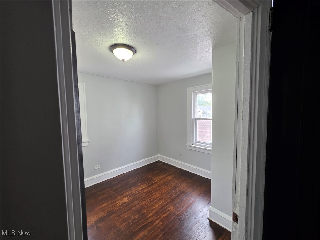 991 Helmsdale Road Cleveland, OH 44112 - Photo 23 of 39 Empty room featuring a textured ceiling and dark wood-type flooring