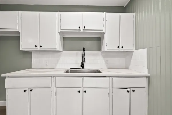 a kitchen with white cabinets and sink