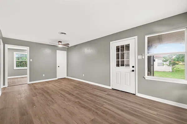 a view of an empty room with a window and wooden floor