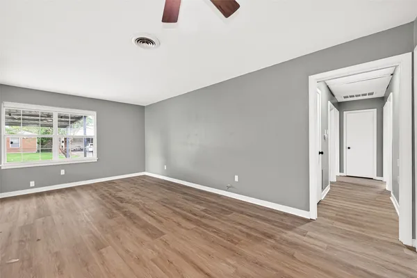 a view of an empty room with wooden floor and a window